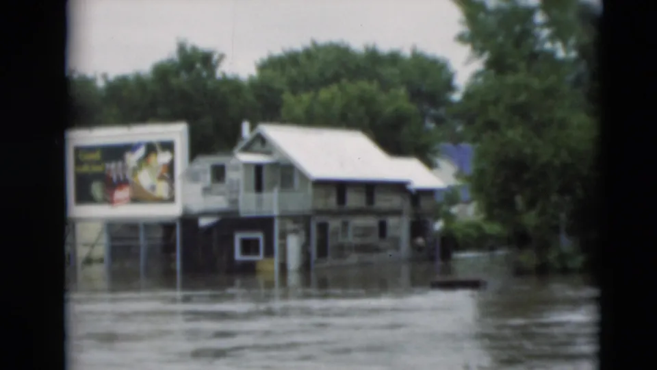 1951 Paducah, Kentucky flood footage showing muddy water around homes, trees, and a roadside billboard.