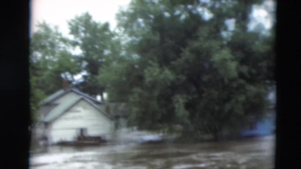 1951 Paducah, Kentucky 8mm frame with a small house, dense trees, and muddy floodwater covering the foreground.