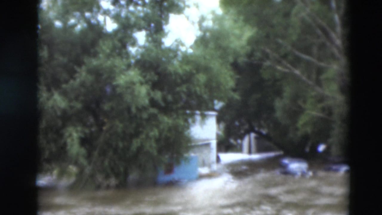 A Paducah residential area appears inundated, with water around houses and trees in grainy 8mm footage from 1951.