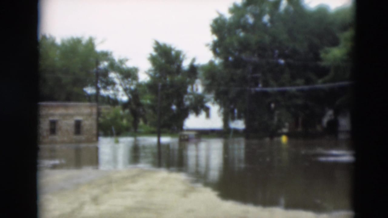 1951 Paducah, Kentucky flood scene with water across a residential area, trees reflected in the water, and a small structure at left.
