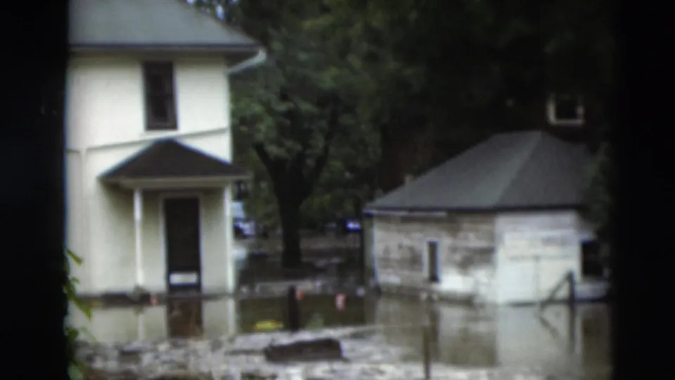 A 1951 Paducah residential flood scene shows water reaching buildings while trees and debris frame the view.