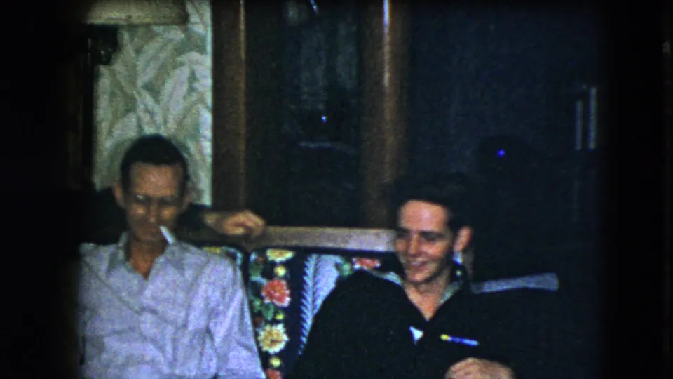 In the final frame, one man smokes while another smiles beside him on the floral couch in the Cleveland family living room.