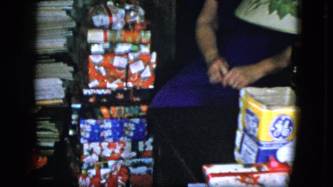 1951 Cleveland frame with a seated woman, stacked holiday packages, and a visible GE-branded box inside a home.