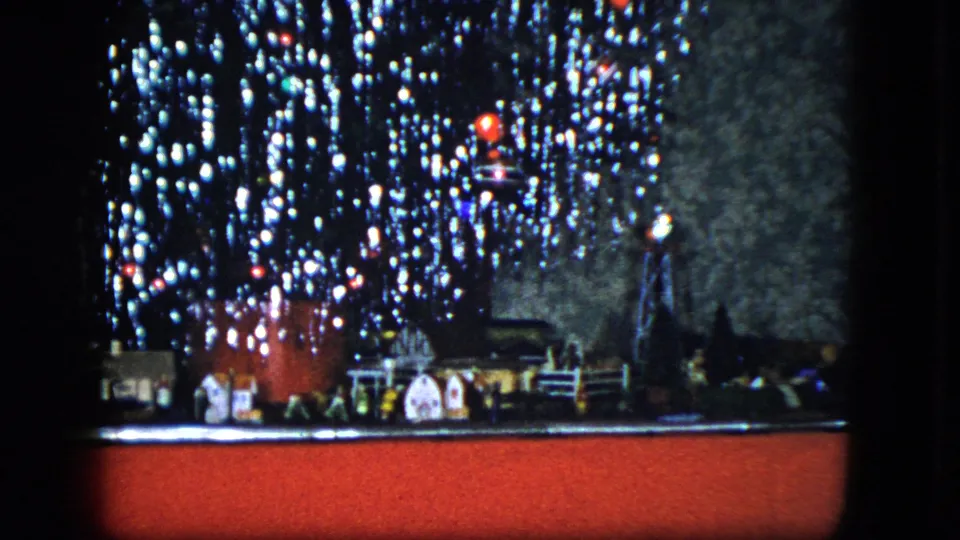 1951 Cleveland home-movie frame focused on the lower tree, miniature houses, toy train elements, and red carpet.
