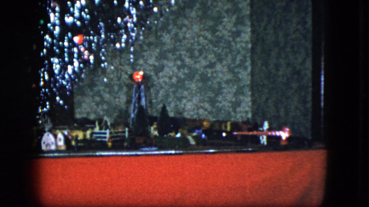 Miniature train layout with tree lights, small buildings, and red base.