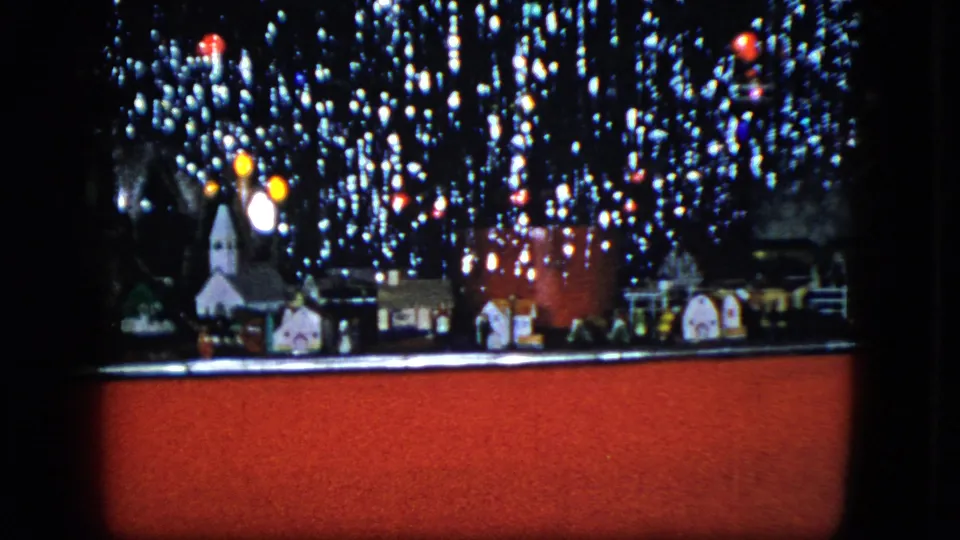 1951 Cleveland 8mm frame showing a miniature Christmas village and train display with glowing lights and soft focus.