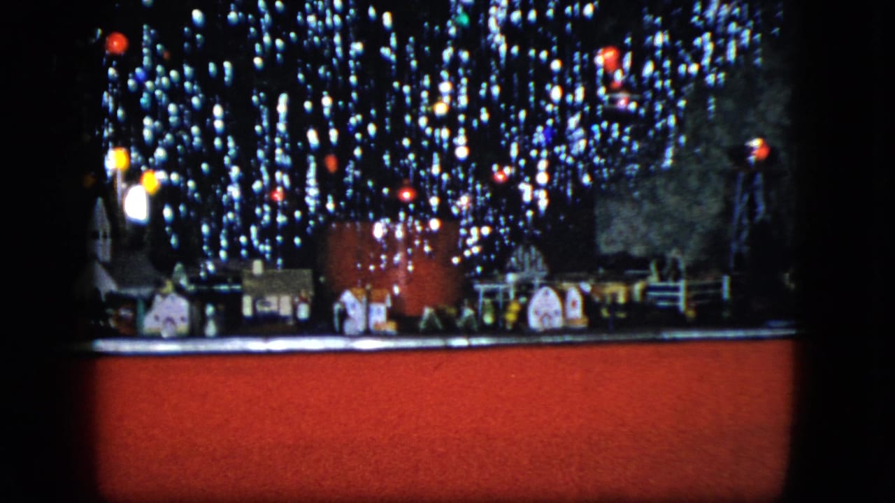1951 Cleveland home-movie frame showing a miniature train village beneath sparkling Christmas tree lights.
