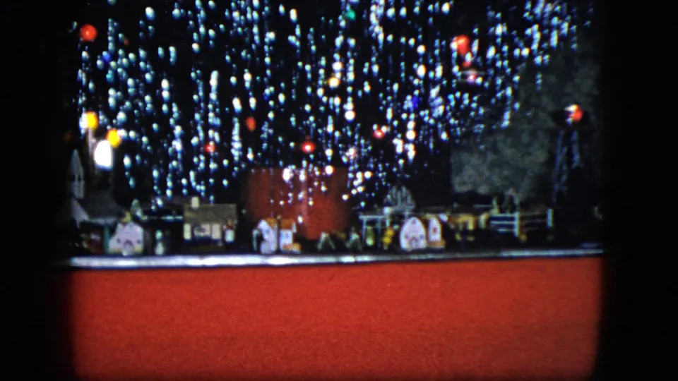 1951 Cleveland home-movie frame showing a miniature train village beneath sparkling Christmas tree lights.