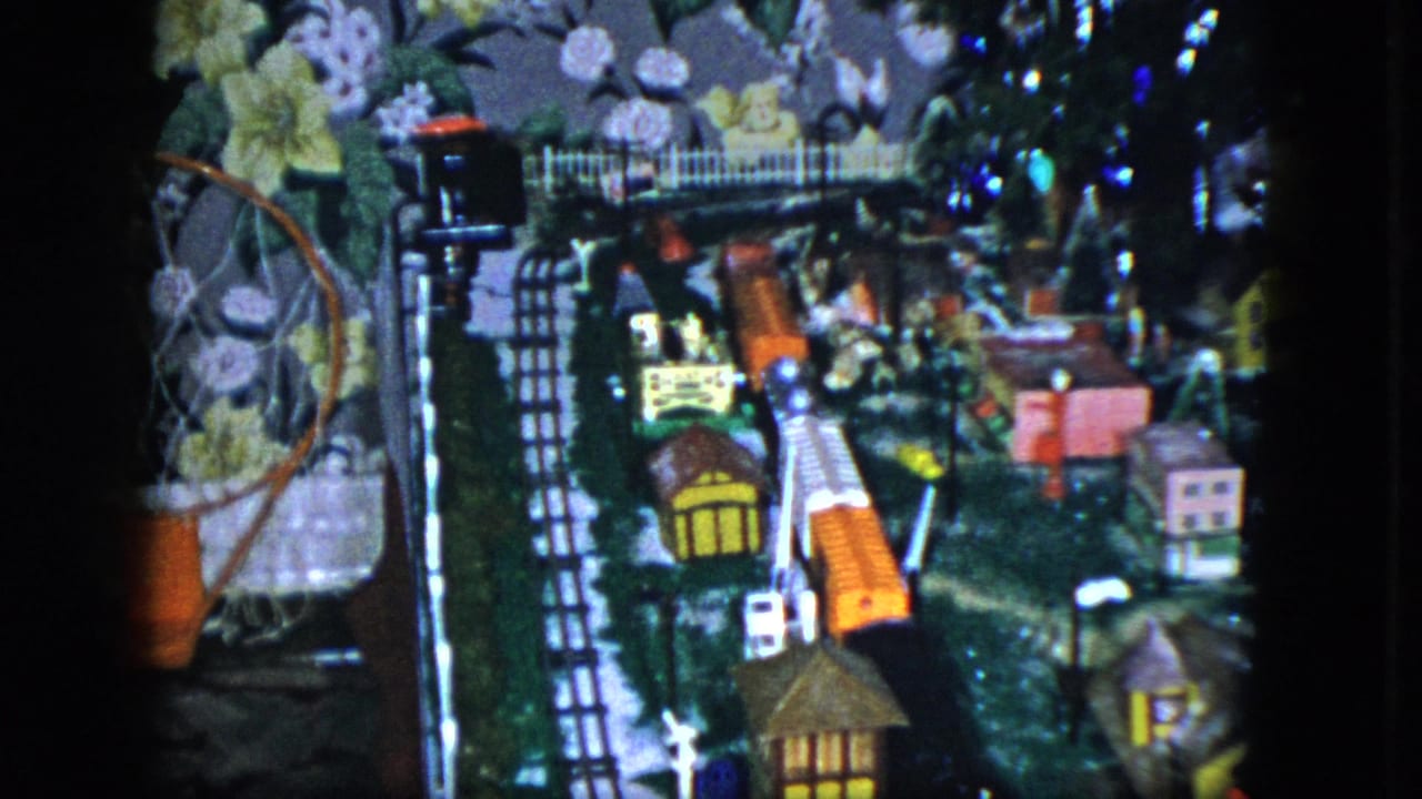 1951 Cleveland frame of a miniature railroad display with lit buildings, track lines, and colorful small structures.