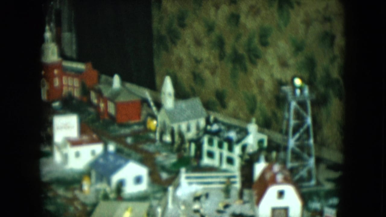 Miniature town with a church-like building, small houses, track, and a gray tower.