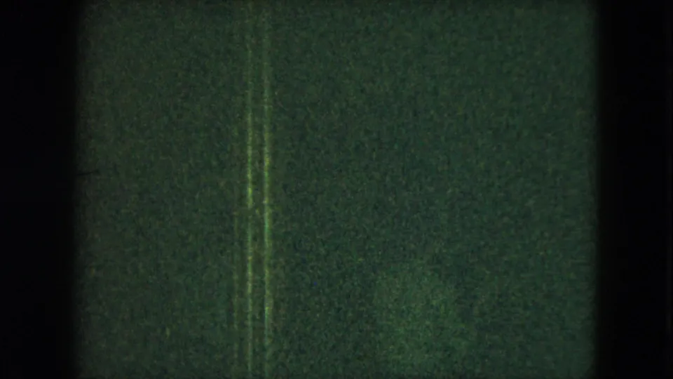 Very dark 1951 Cleveland 8mm frame with green tint, heavy grain, vertical film edges, and only faint interior forms visible.