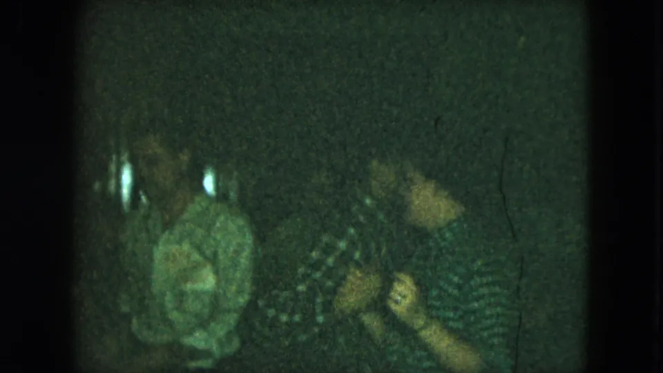 Green-tinted 1951 Cleveland home-movie frame showing several people in a dark nightclub or party setting, with patterned clothing and bright reflections.