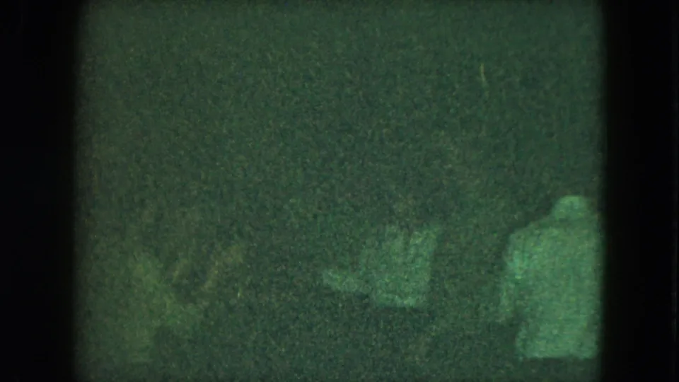 1951 Cleveland home-movie still with adults dancing under low light and heavy grain.