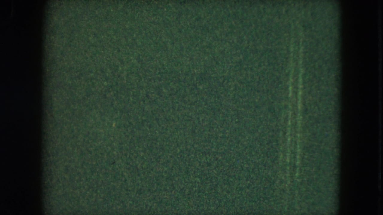 Dim 1951 Cleveland home-movie frame with green cast, heavy grain, scratches, and only faint shapes visible in the darkness.