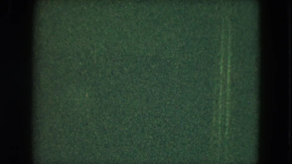 Dim 1951 Cleveland home-movie frame with green cast, heavy grain, scratches, and only faint shapes visible in the darkness.