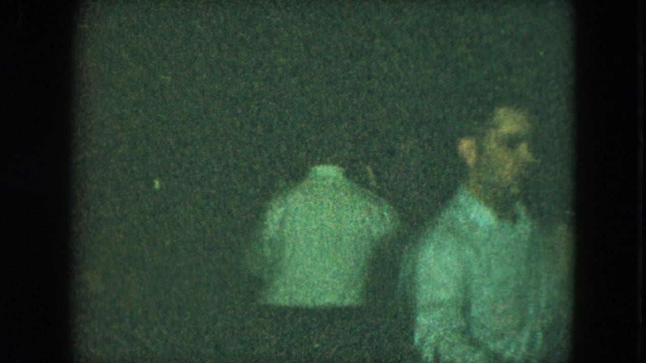 Cleveland, Ohio 1951 home-movie frame showing two adults near a dark wall during an indoor social dance gathering.