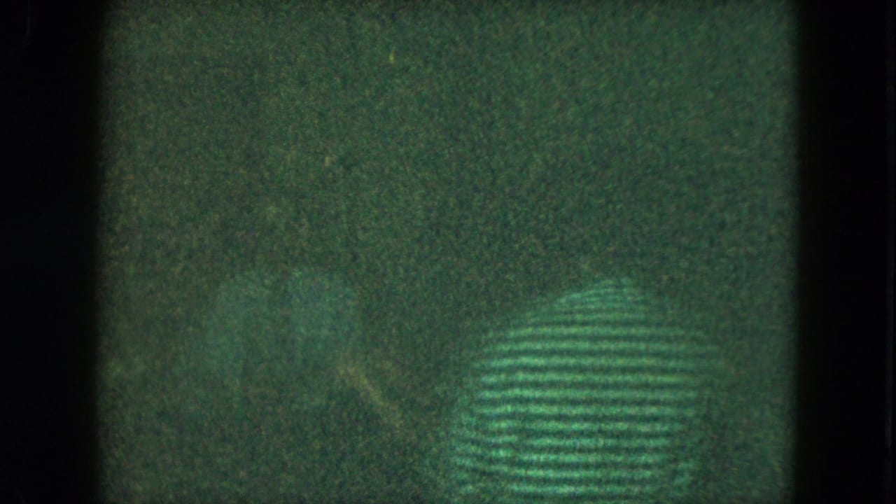 Dark green-tinted frame with window-like divisions and an indistinct patterned shape.