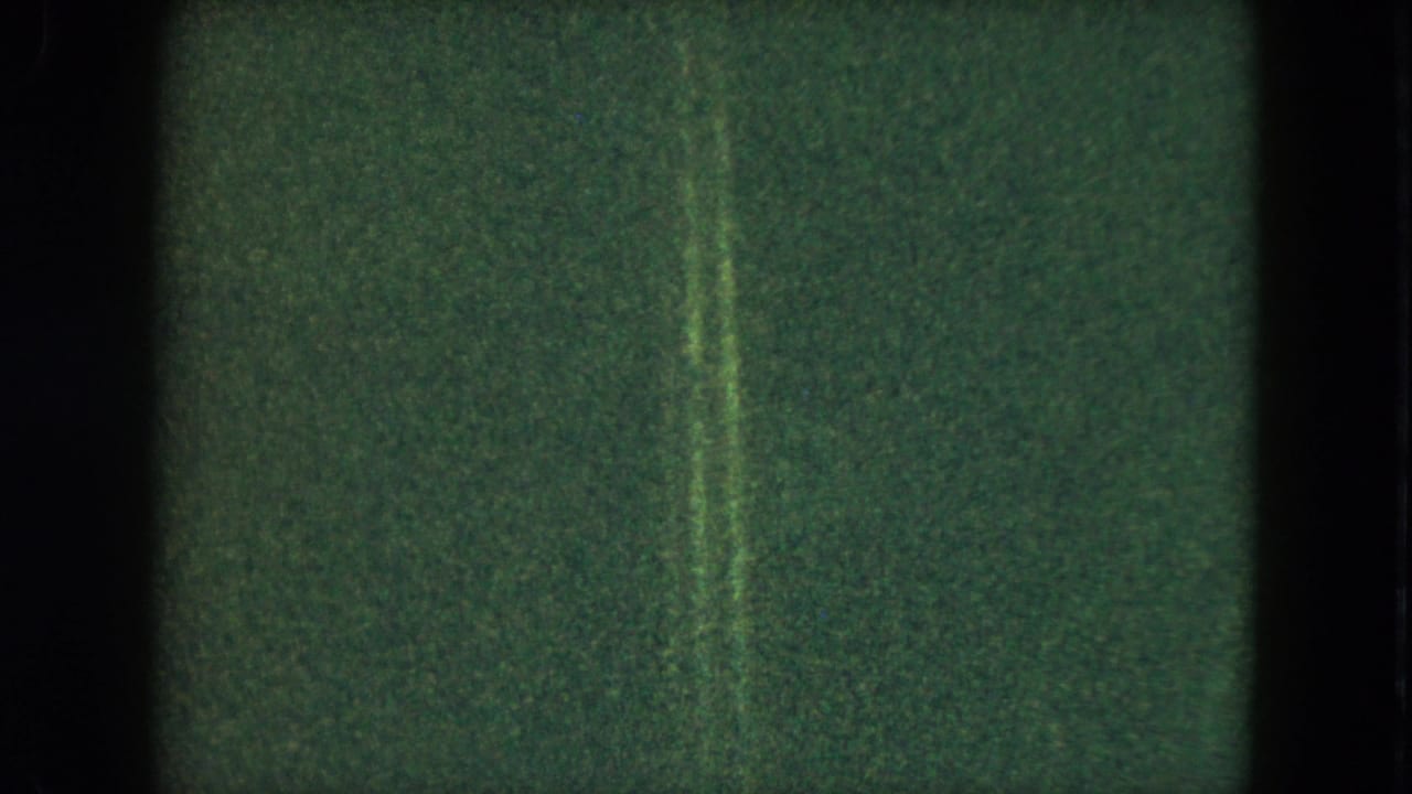 Grainy 1951 Cleveland home-movie frame showing a dim interior field with a narrow vertical light streak.