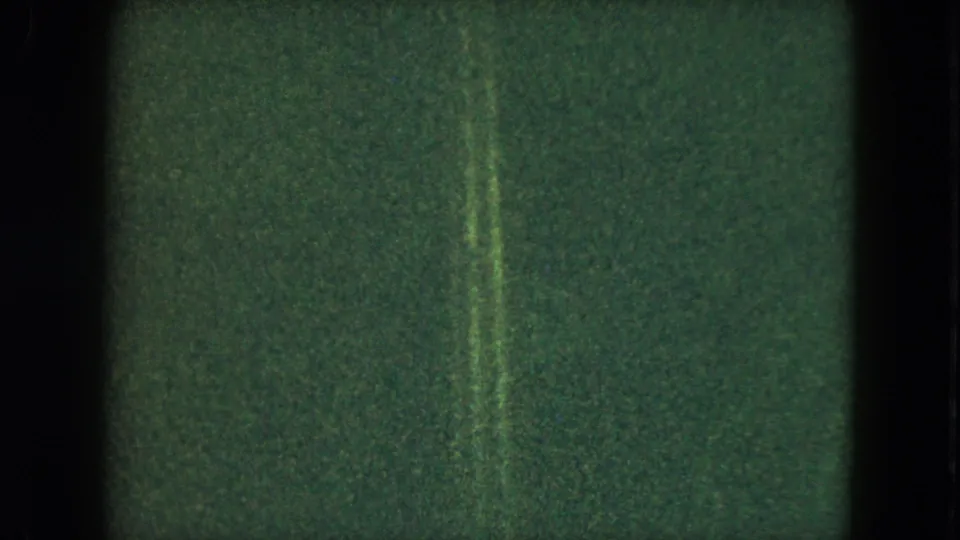 Grainy 1951 Cleveland home-movie frame showing a dim interior field with a narrow vertical light streak.