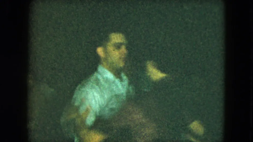 1951 Cleveland home-movie frame showing a blurred man in a light shirt moving with raised hands during an indoor social dance.