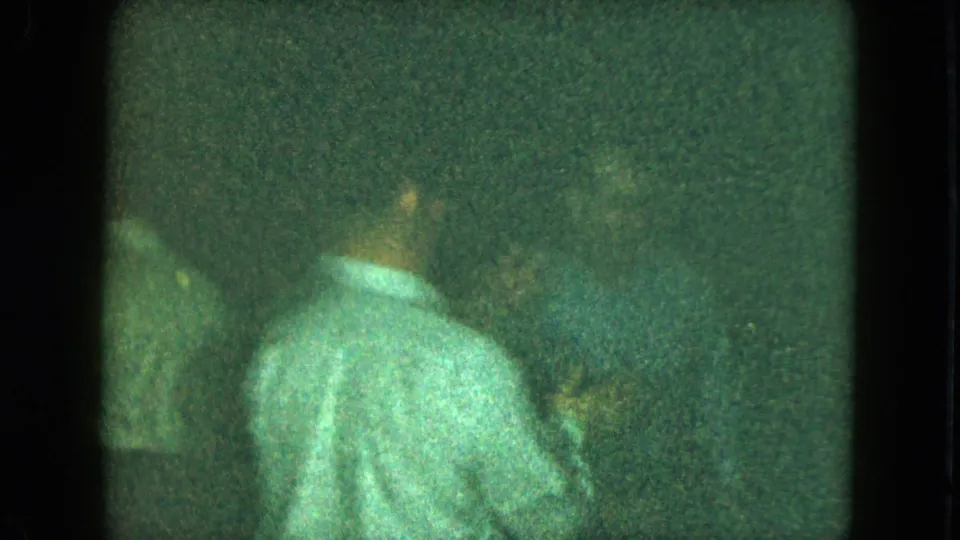 An adult in a light shirt bends or turns away from the camera in the grainy 1951 Cleveland party footage.