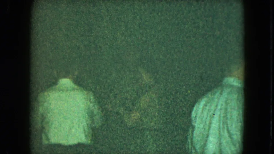 1951 Cleveland 8mm frame with a man seen from behind in a light shirt within a dim interior.