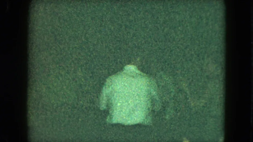 Grainy 1951 Cleveland home-movie frame showing a man from behind in a light shirt against a dark interior.