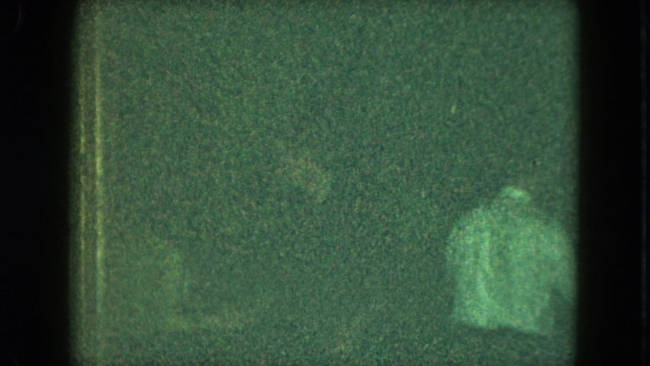 Grainy 8mm frame from the Cleveland clip with an indistinct person moving in low light.