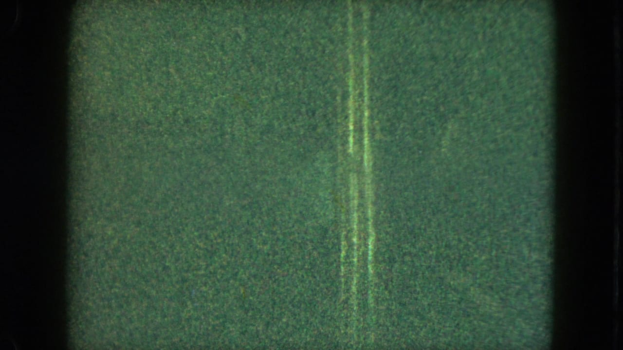 1951 Cleveland 8mm frame with dark low-light exposure, vertical artifacts, and a faint small figure near the left edge.