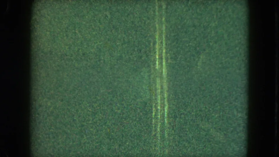 1951 Cleveland 8mm frame with dark low-light exposure, vertical artifacts, and a faint small figure near the left edge.