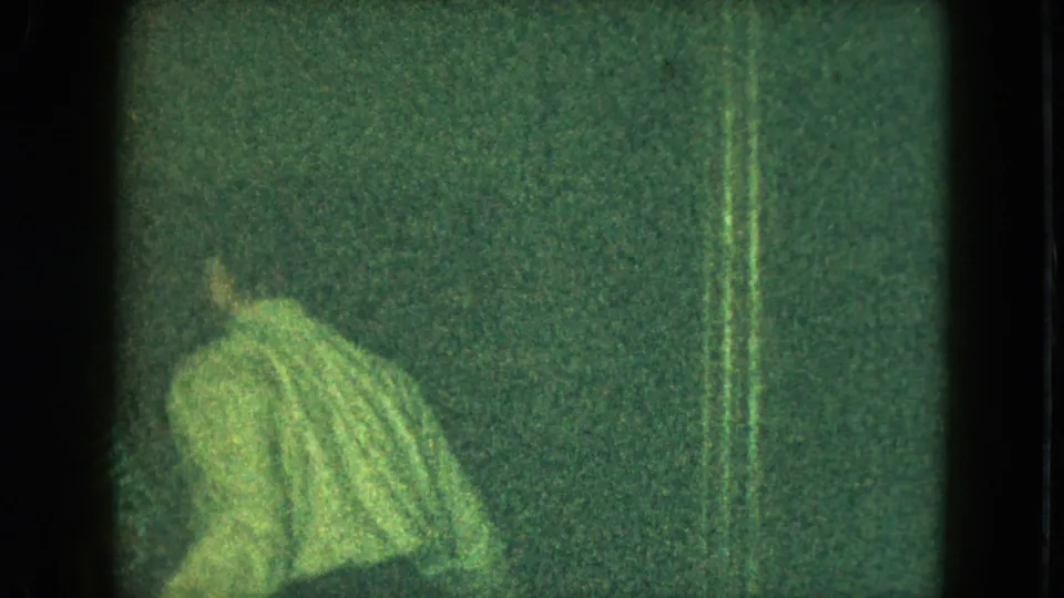 A small figure in a striped sweater appears in a dark 1951 Cleveland home-movie frame with heavy grain and vertical artifacts.