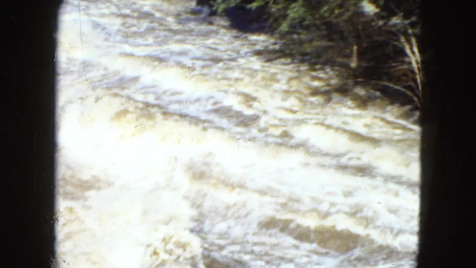 Rushing white water fills the frame in this 1951 Cleveland 8mm home-movie still, with dark brush and strong overexposure.