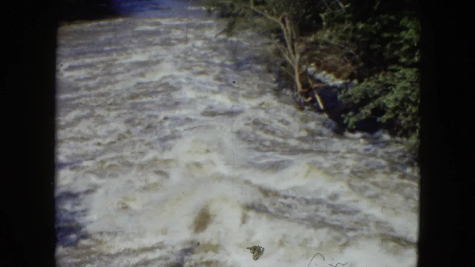 The closing frame shows churning rapids beside dense greenery, with visible 8mm grain and rounded black borders.