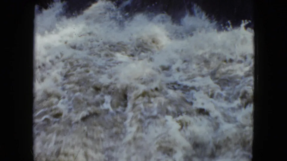 Vintage 8mm frame from the 1951 Cleveland clip showing foamy rapids moving over uneven rocks.