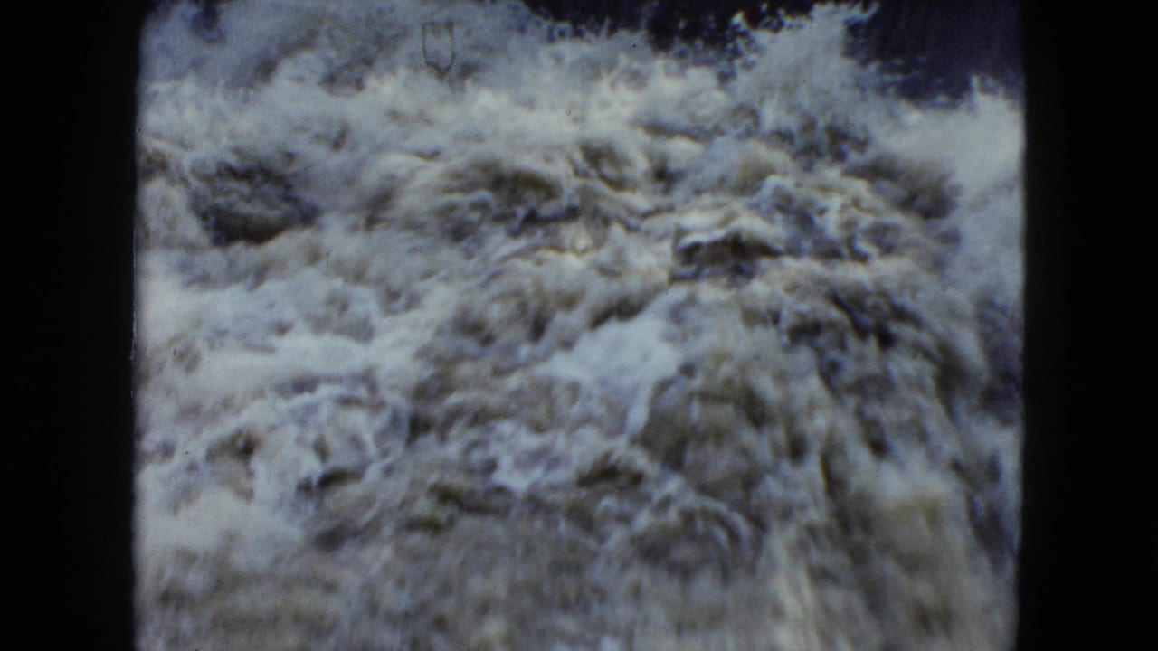 Rough, foamy water rushes across the frame.