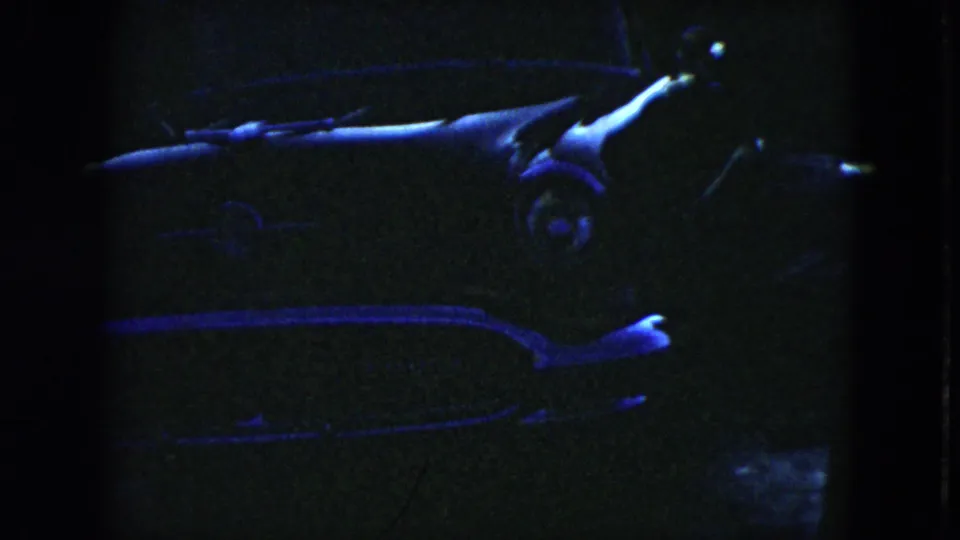 A very dark 1951 Cleveland frame shows the car in low light, with a partially visible person near the vehicle.