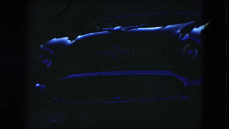 Low-exposure 1951 Cleveland frame showing the side of a parked 1950s car, with blue light catching the roofline, side panel, and trim.