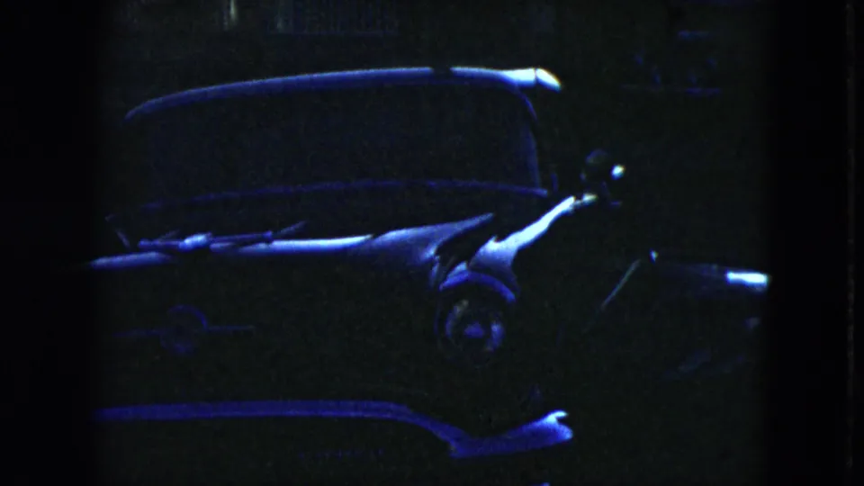 Final low-light frame showing the parked 1950s car with blue highlights along the hood, side, windshield, and reflective chrome details.