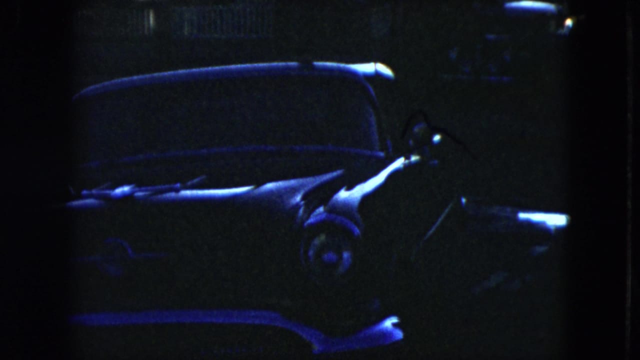Dark parked vintage sedan with faint blue highlights and shadowed background.