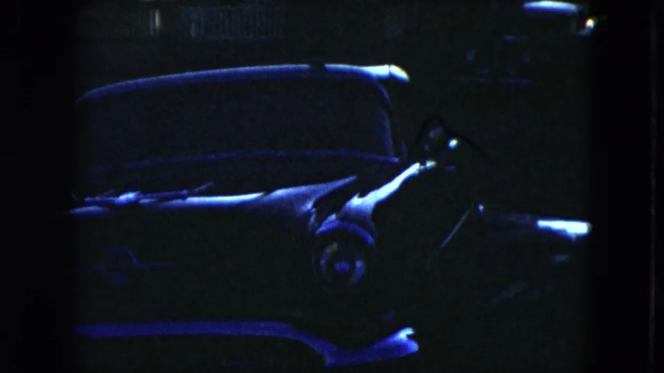 1951 Cleveland home-movie frame showing a dark parked sedan, chrome trim, windshield, and heavy blue low-light cast.