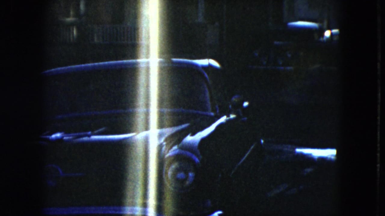 1951 Cleveland 8mm frame with a parked sedan partly obscured by a bright vertical flare or light leak.