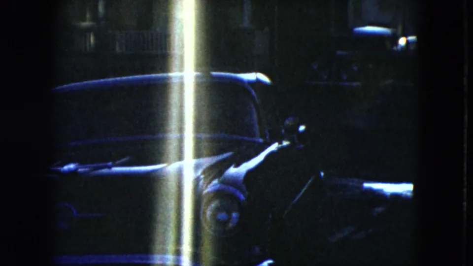 1951 Cleveland 8mm frame with a parked sedan partly obscured by a bright vertical flare or light leak.