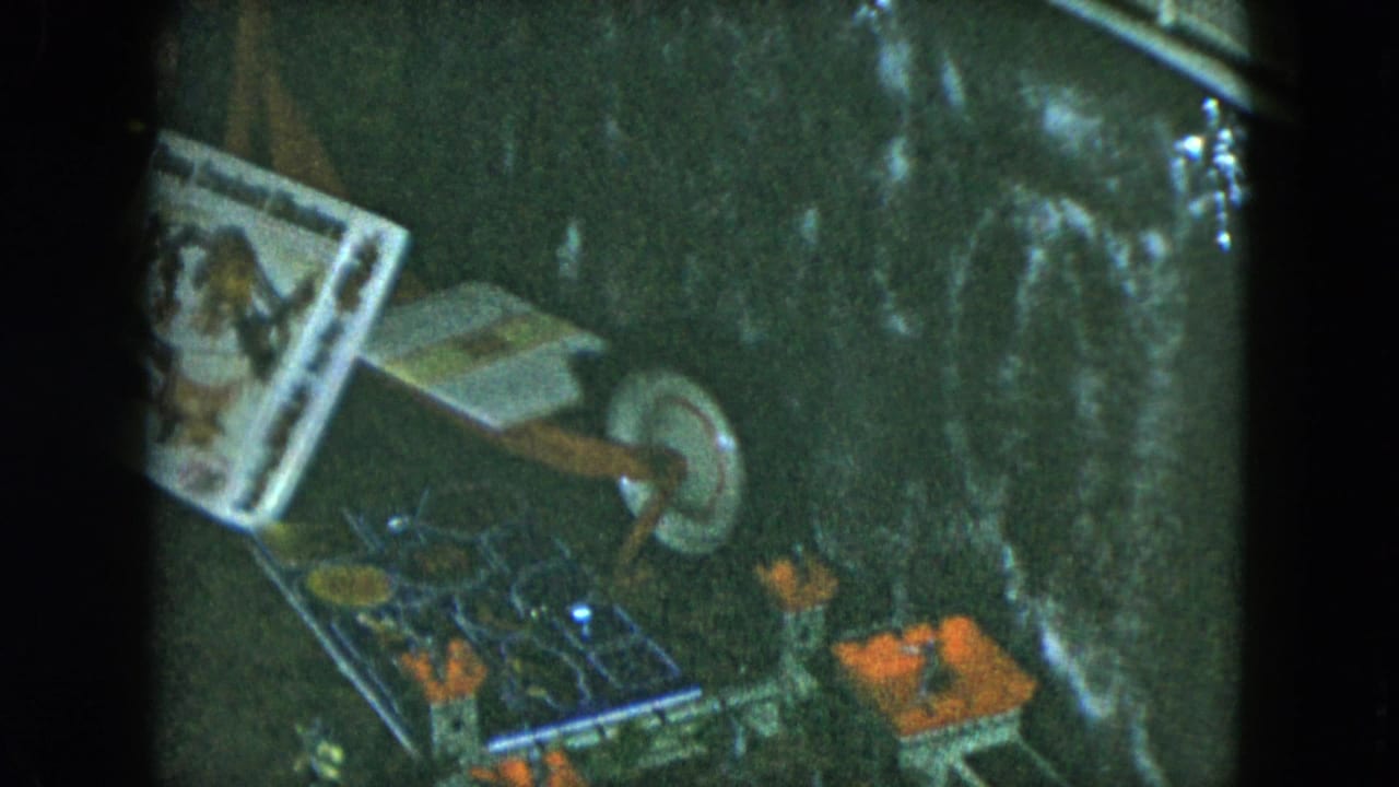 1951 Cleveland 8mm frame showing a toy castle, circular spinner game, and assorted small toys on a dark surface.