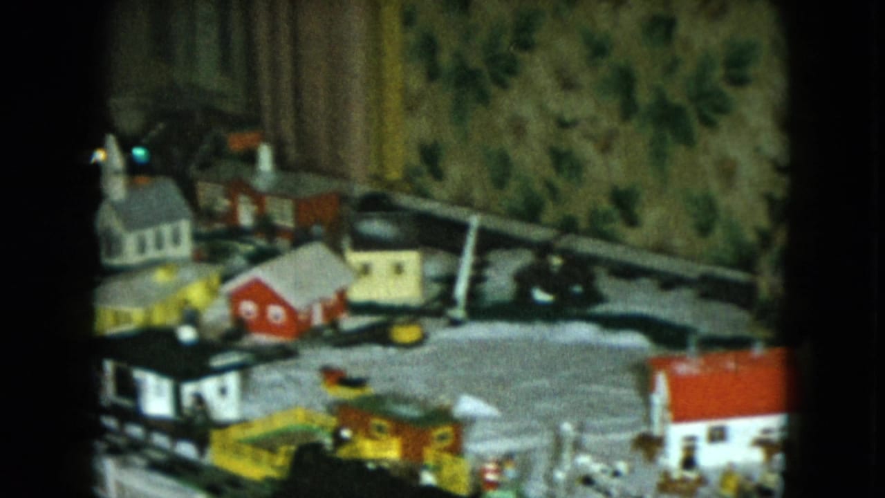 1951 Cleveland frame showing a wider section of the tabletop train layout with miniature houses, tracks, and a bridge-like structure.