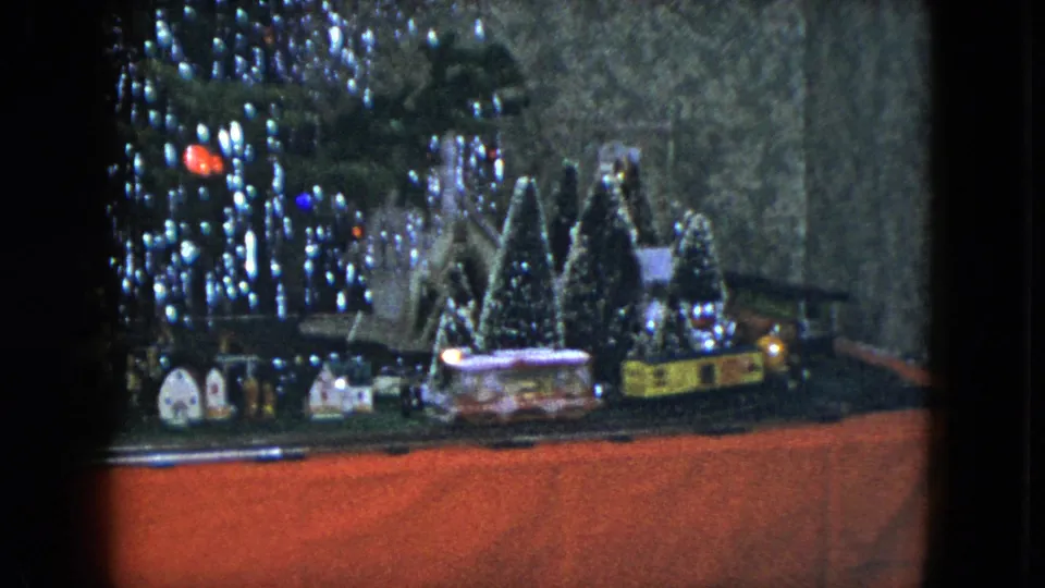 A 1951 Cleveland holiday train display shows a miniature landscape with houses, evergreen trees, train cars, and glittering lights.