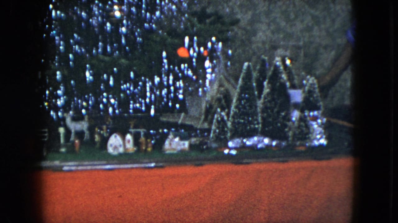 1951 Cleveland holiday display with a lit Christmas tree, train track, small houses, deer figures, and snowy miniature trees.