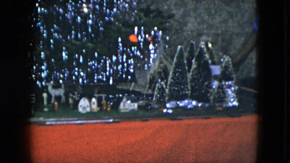 1951 Cleveland holiday display with a lit Christmas tree, train track, small houses, deer figures, and snowy miniature trees.