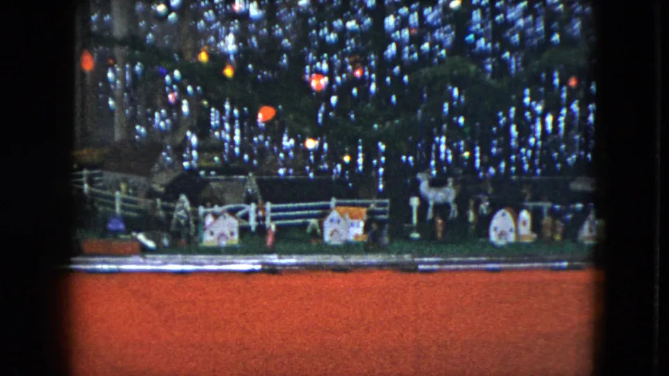 1951 Cleveland frame of a home Christmas train display, with the miniature village and reindeer figures seen below dense tinsel.