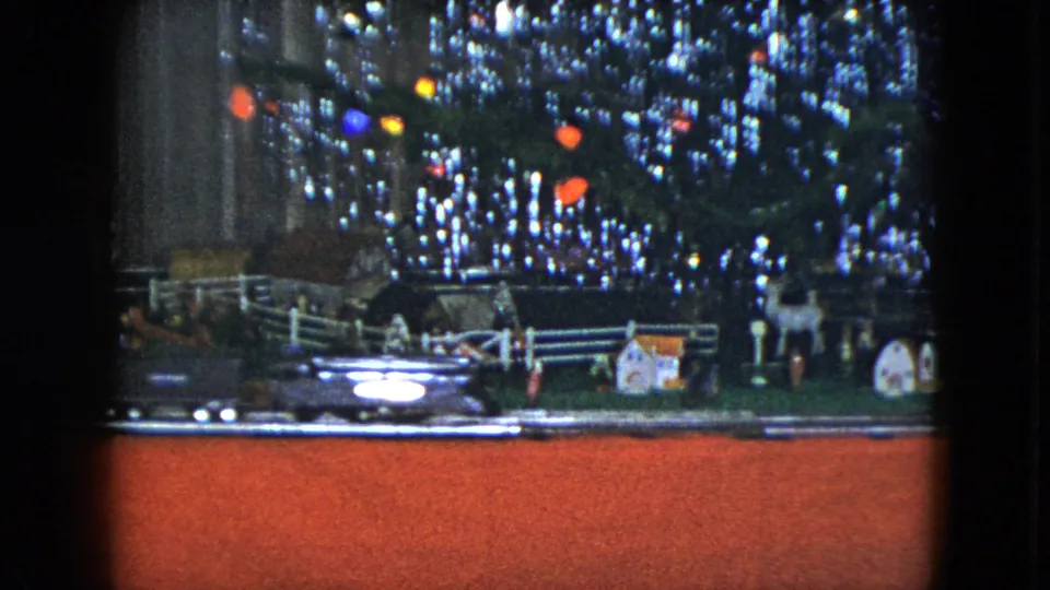 1951 Cleveland home-movie frame showing the model train passing the miniature display under the decorated Christmas tree.