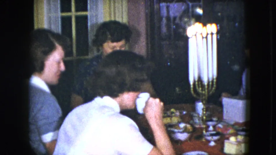 Women sit around a candlelit dining table in a 1951 Cleveland home-movie dinner scene.